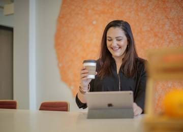 Woman works on laptop while drinking coffee